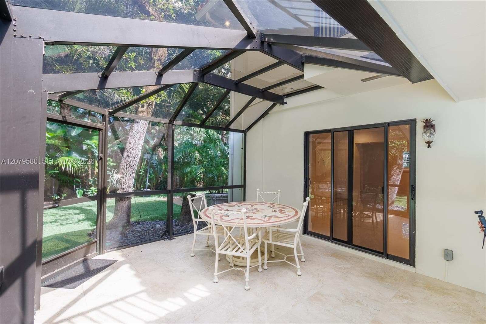 Screened-in patio featuring a vaulted geometric metal frame, glass panels, stone-finish flooring, and sliding glass doors