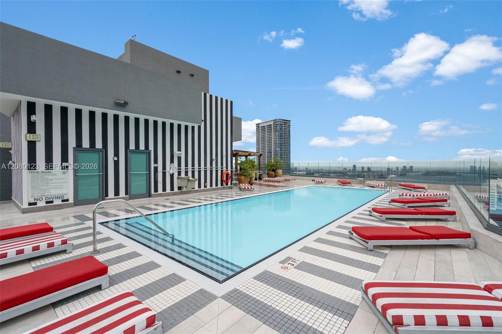 Rooftop pool deck with city views and signature red-striped chaise lounges at SLS Brickell Dua.