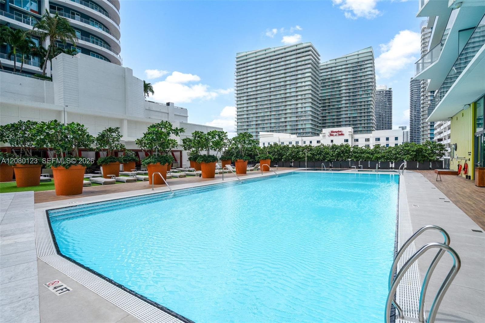 Hotel-style pool with chaise lounges and tropical landscaping at SLS Brickell Dua.