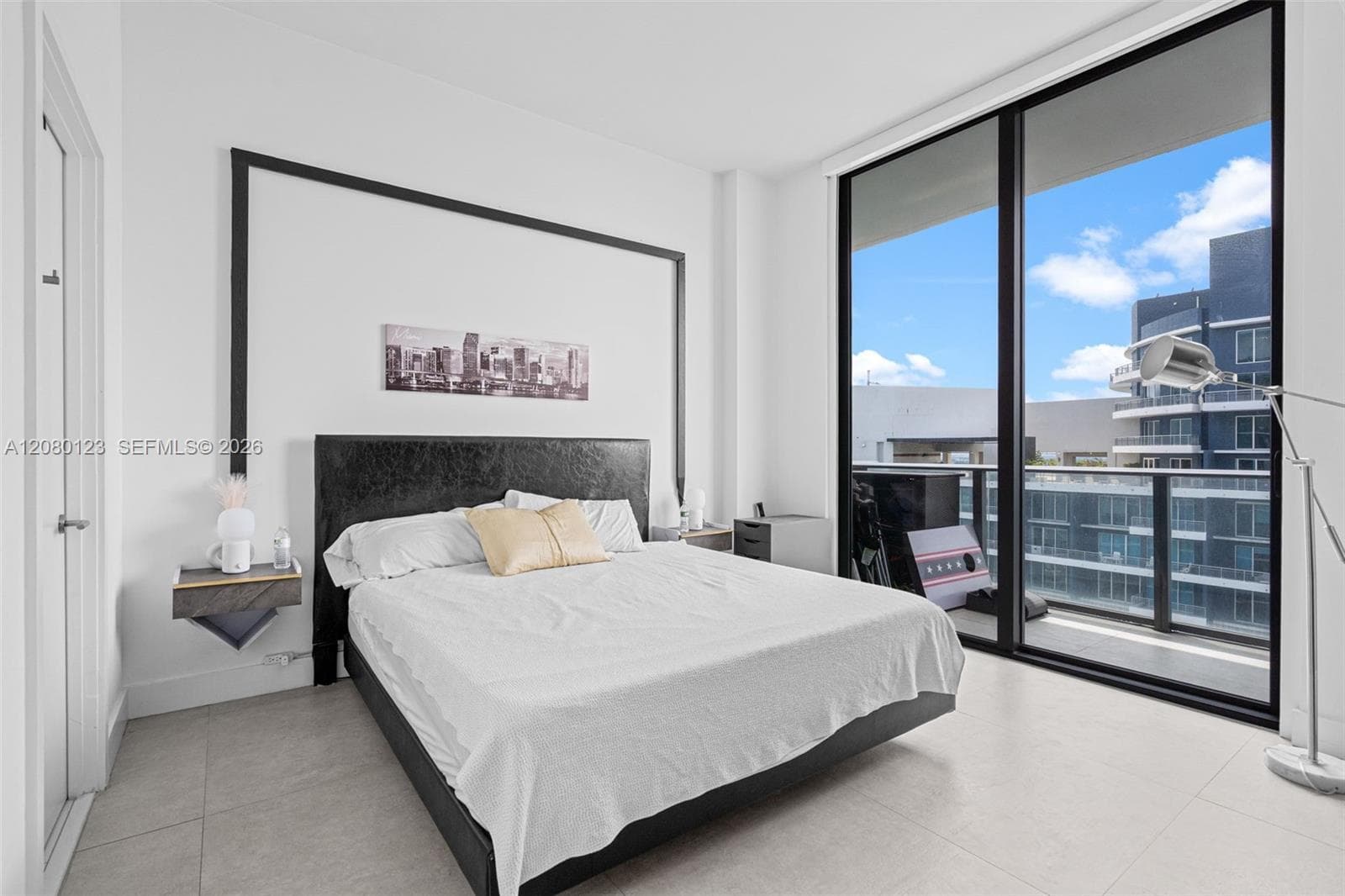Guest bedroom with leather headboard, custom skyline art, and private terrace access at this Brickell penthouse.