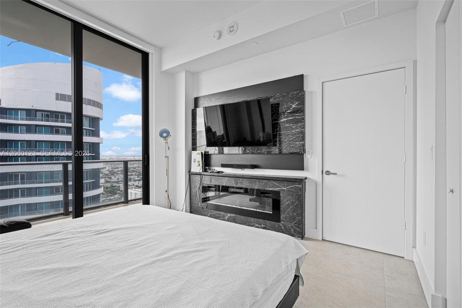 Primary suite with mounted TV, custom built-in closets, and floor-to-ceiling glass opening to the private terrace at SLS Brickell Dua PH-5209.