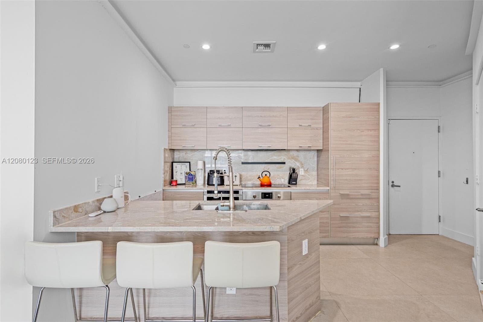 Chef's kitchen with marble waterfall island, breakfast bar seating, and integrated Bosch appliances at SLS Brickell Dua.