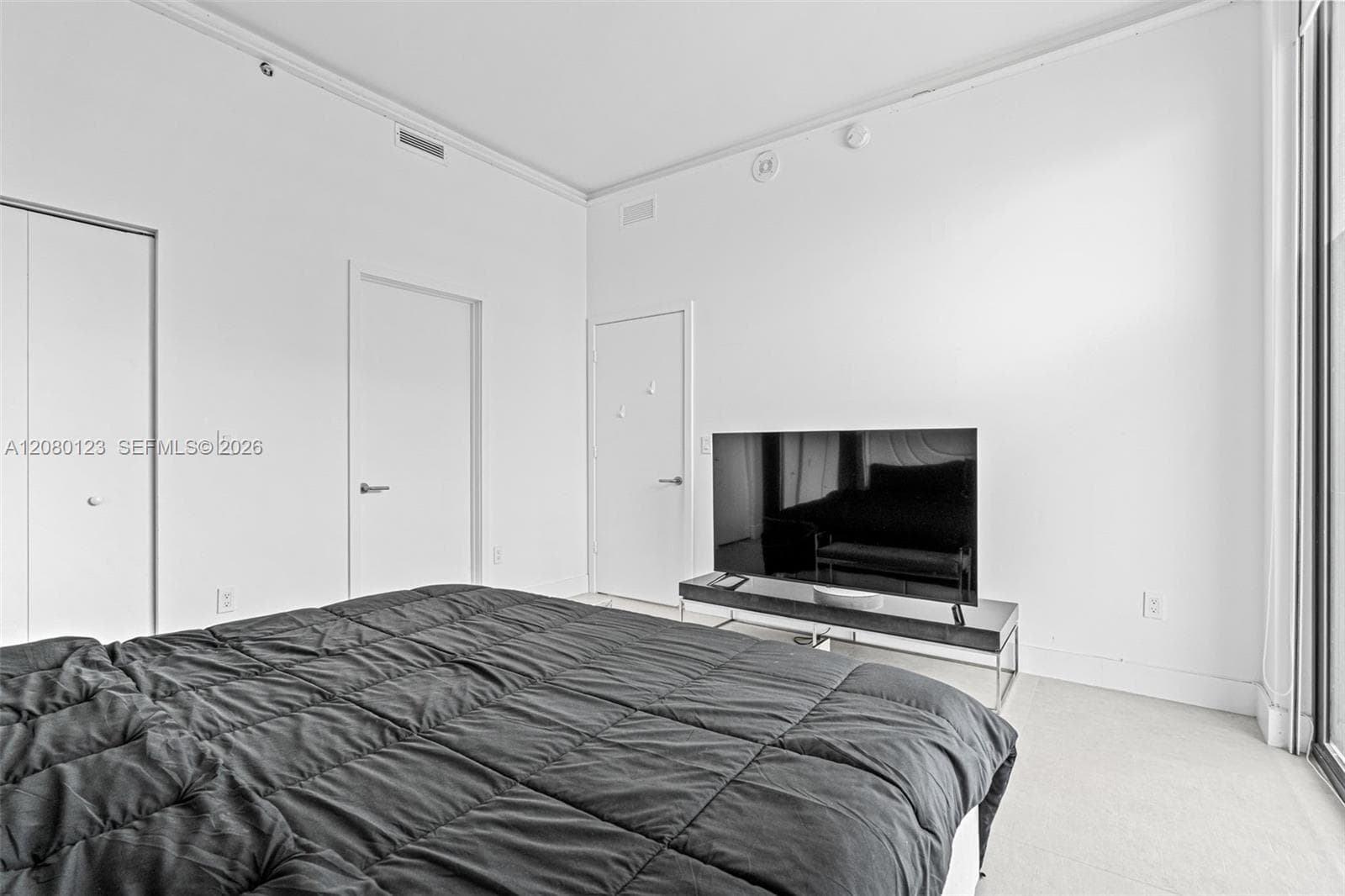 Penthouse bedroom with king bed, mounted TV, and panoramic skyline views from the 52nd floor at PH-5209.