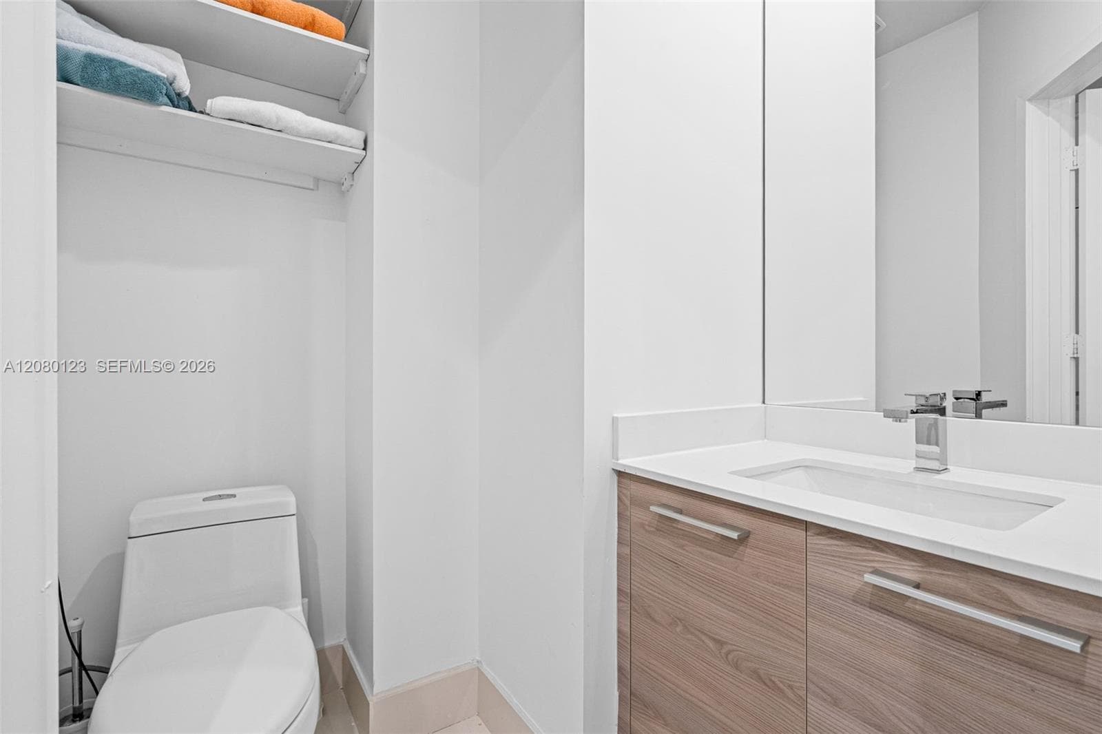 Powder room with floating vanity, sleek mirror, and built-in linen storage at this Brickell penthouse.