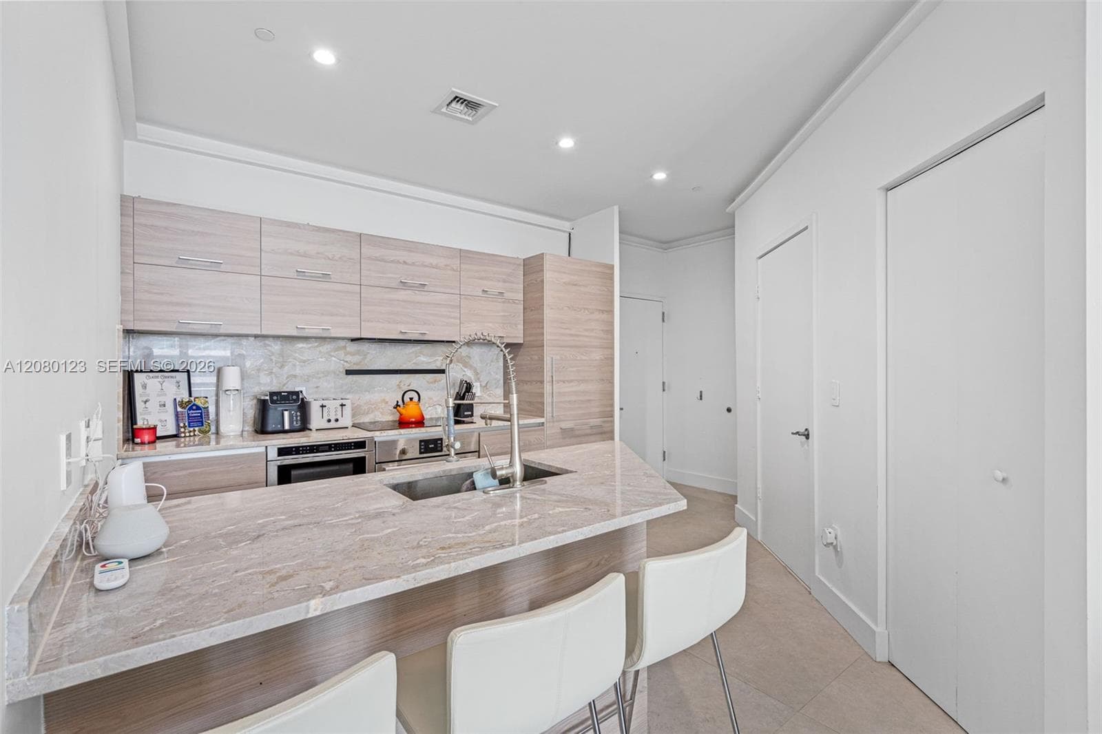 Italian-style kitchen featuring oversized marble island, Bosch cooktop and oven, and counter-height bar seating.