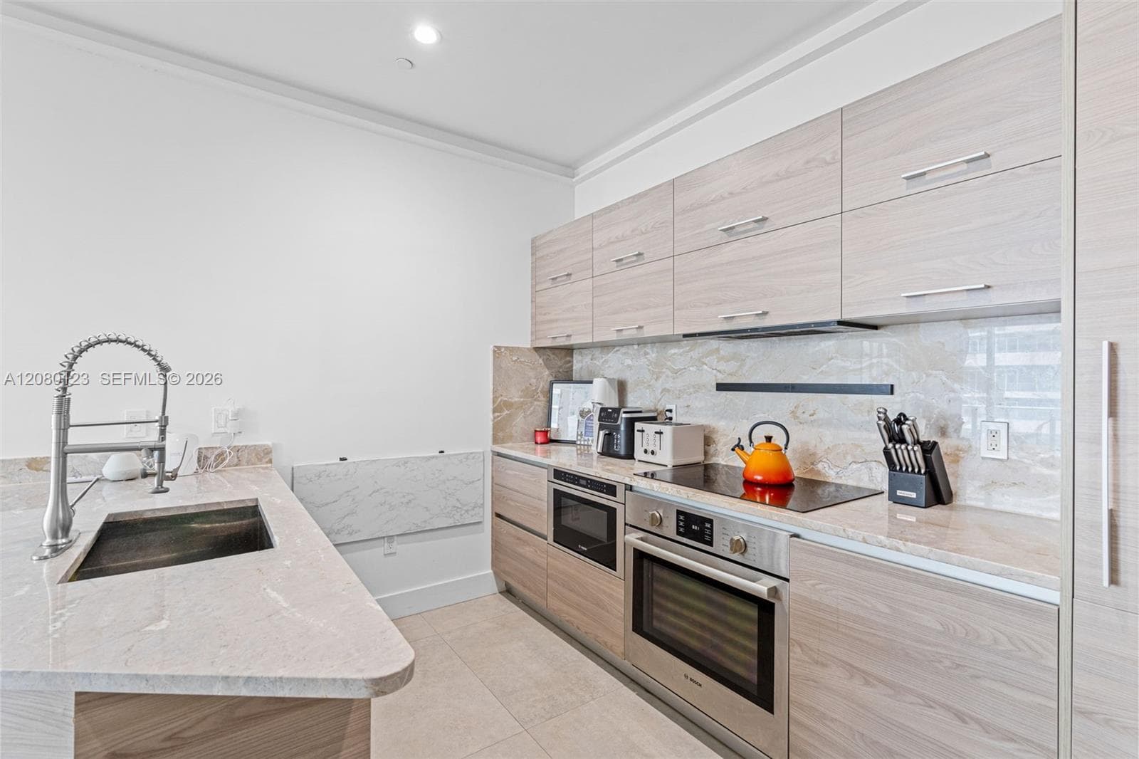 Kitchen detail showing Bosch built-in oven, induction cooktop, and marble counters at SLS Brickell Dua.