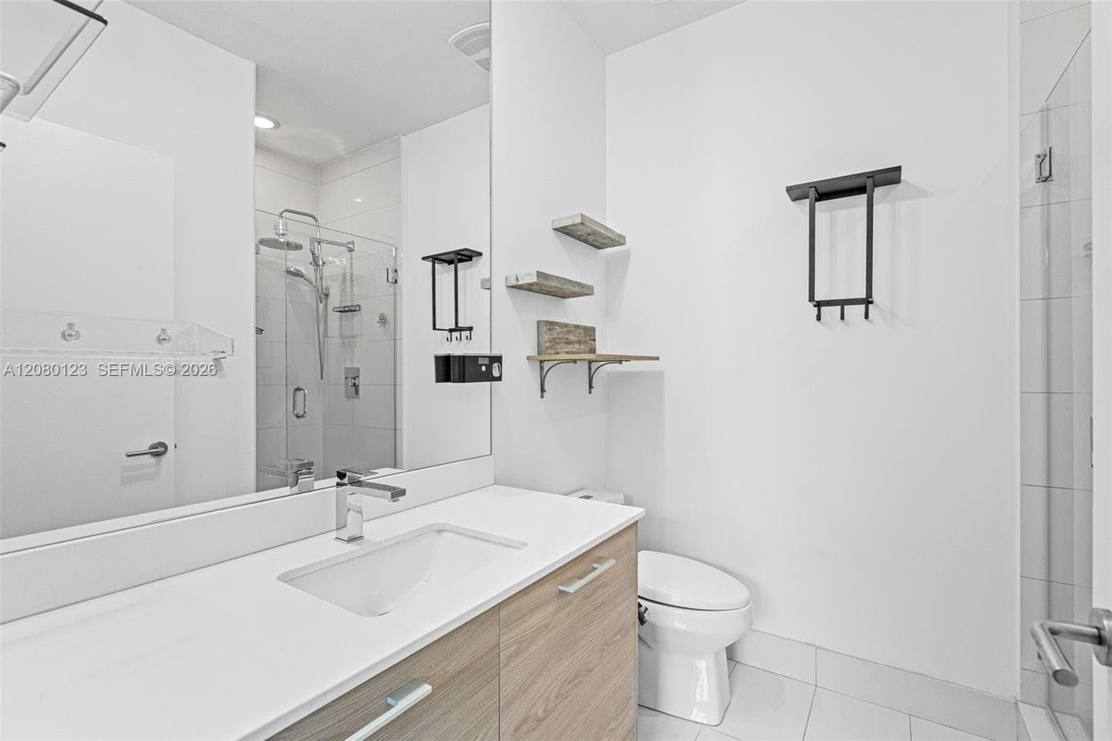 En-suite bathroom with floating wood vanity, quartz counter, and full-height tiled shower at SLS Brickell Dua.