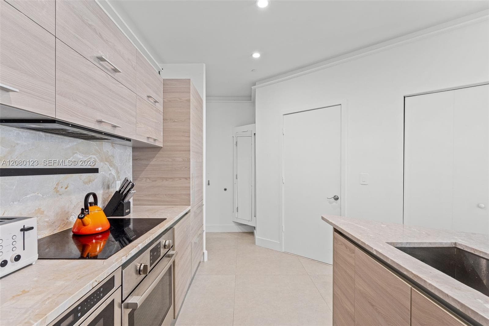 Sleek modern kitchen with marble backsplash, Bosch induction cooktop, and fully integrated appliances.
