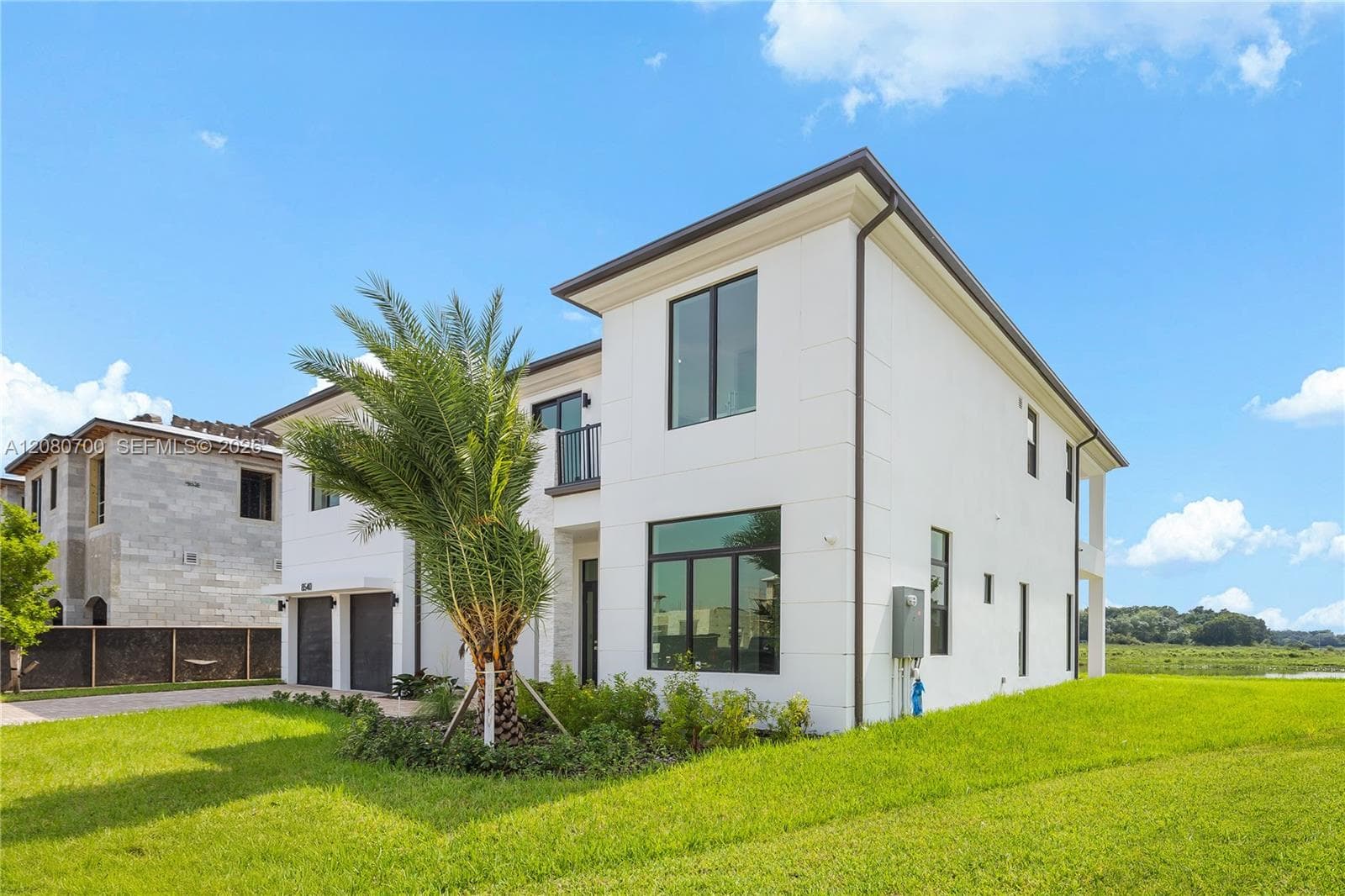 Contemporary two-story residence with a white exterior, dark-framed windows, and a manicured lawn