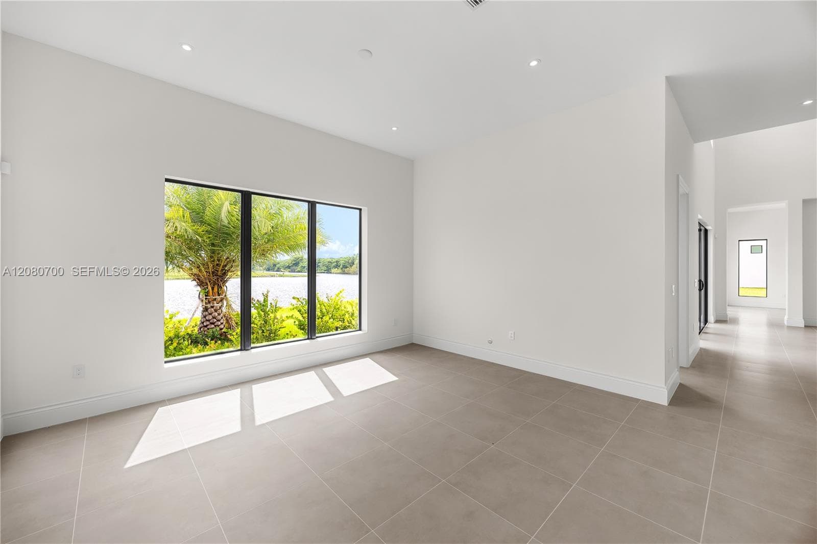 Large window with a black frame, recessed lighting, light-toned tile flooring, and white painted walls