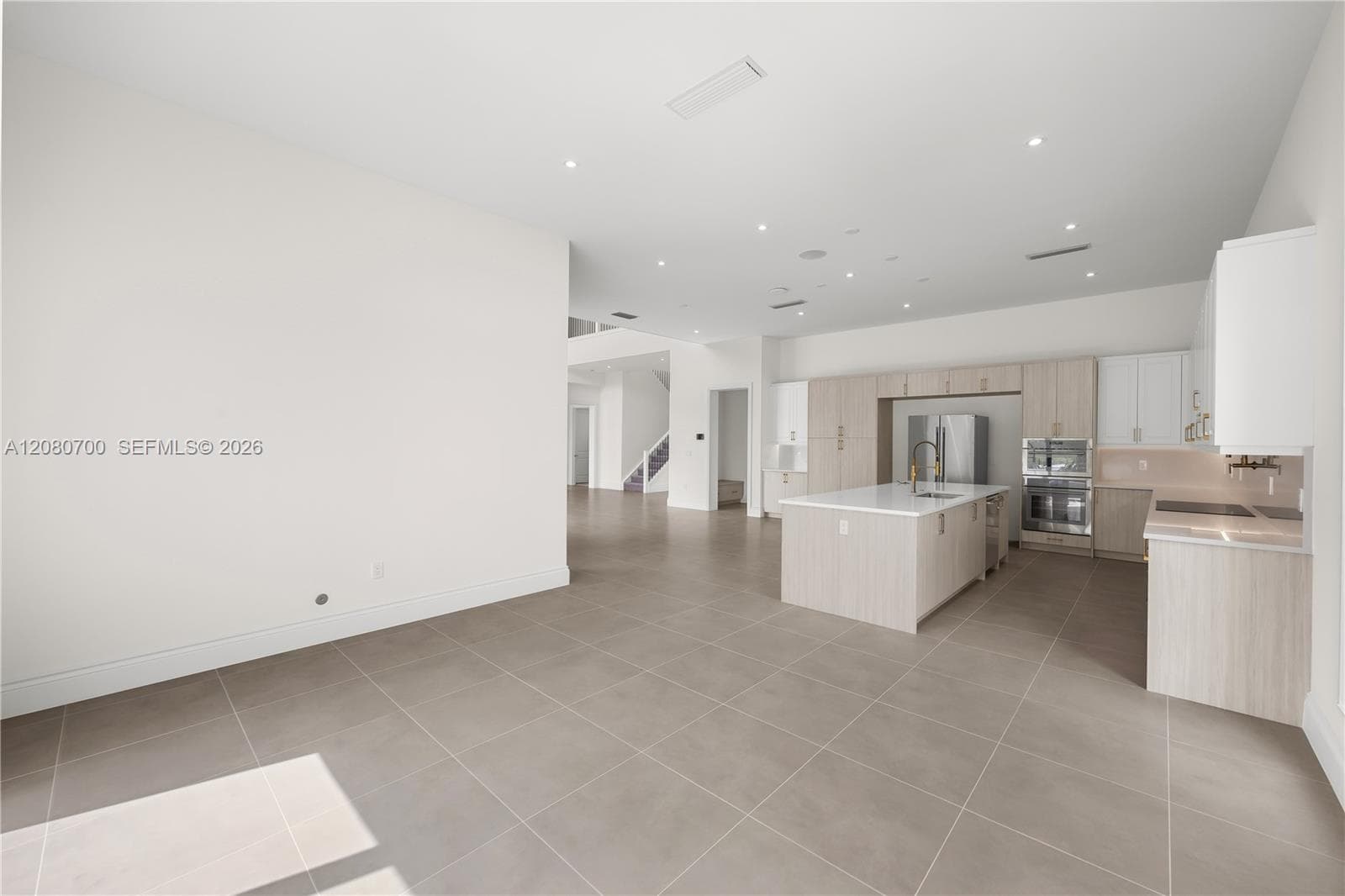 Spacious open-concept interior with large format tile flooring, recessed lighting, and high ceilings
