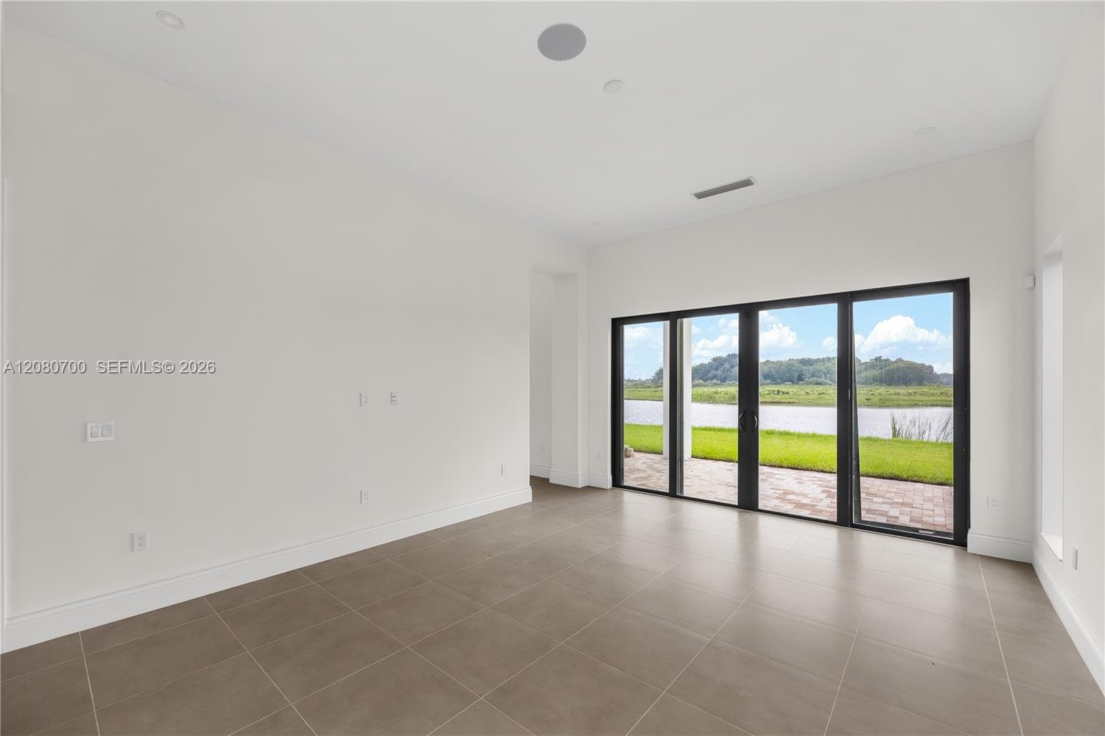 Expansive room featuring large format tile flooring, recessed ceiling lighting, and a multi-panel sliding glass door