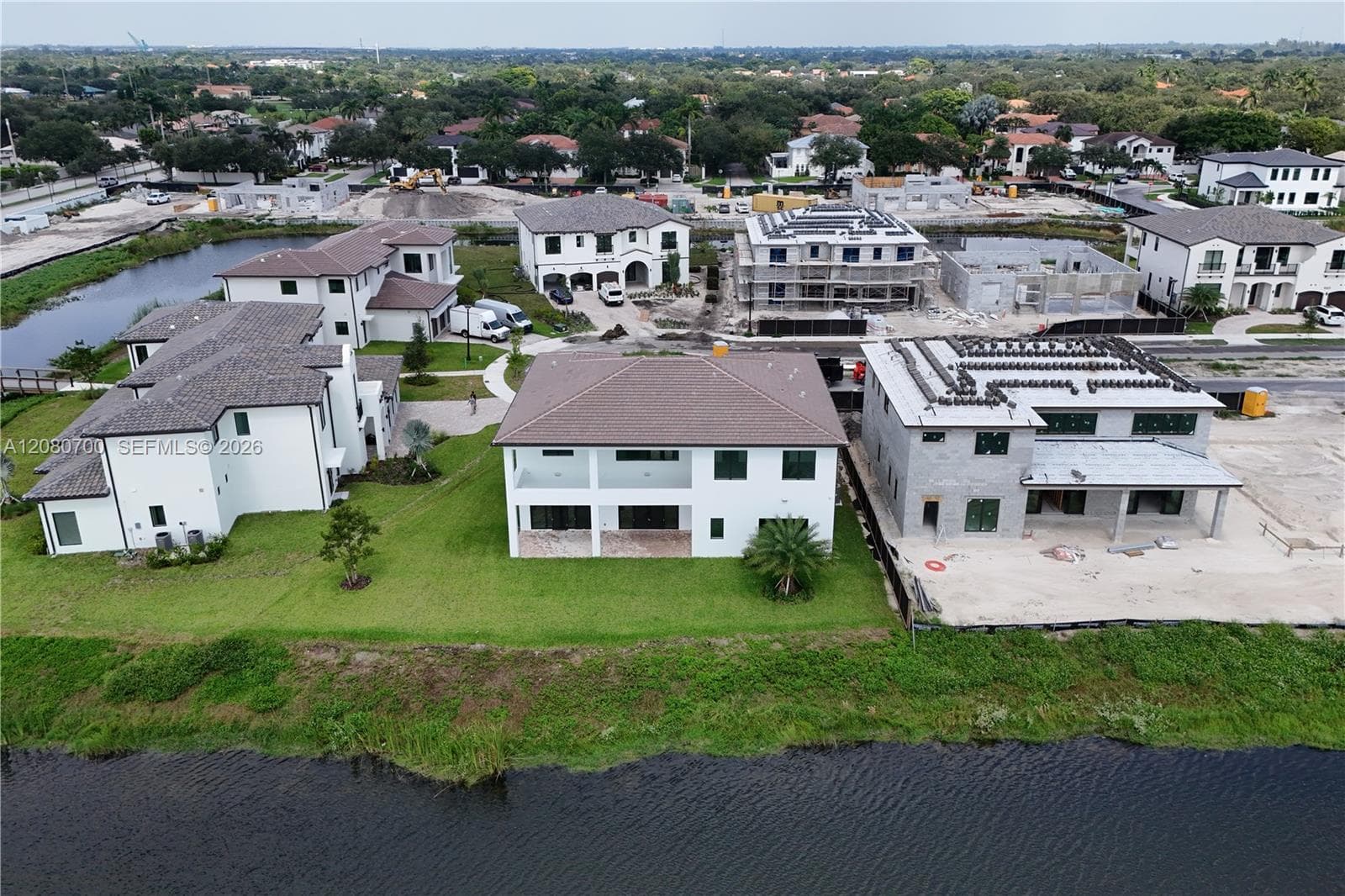 Waterfront property featuring a white stucco exterior and tile roofing