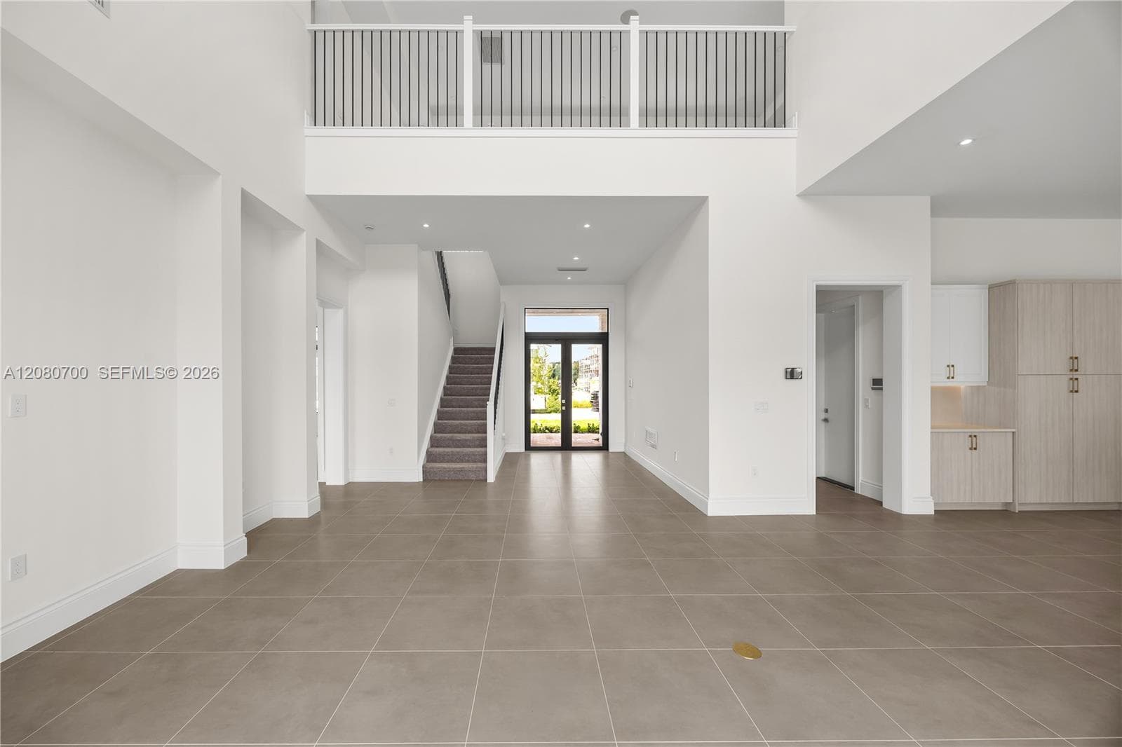 Two-story entry with high ceilings, tile flooring, carpeted staircase, and an open balcony overlooking the space