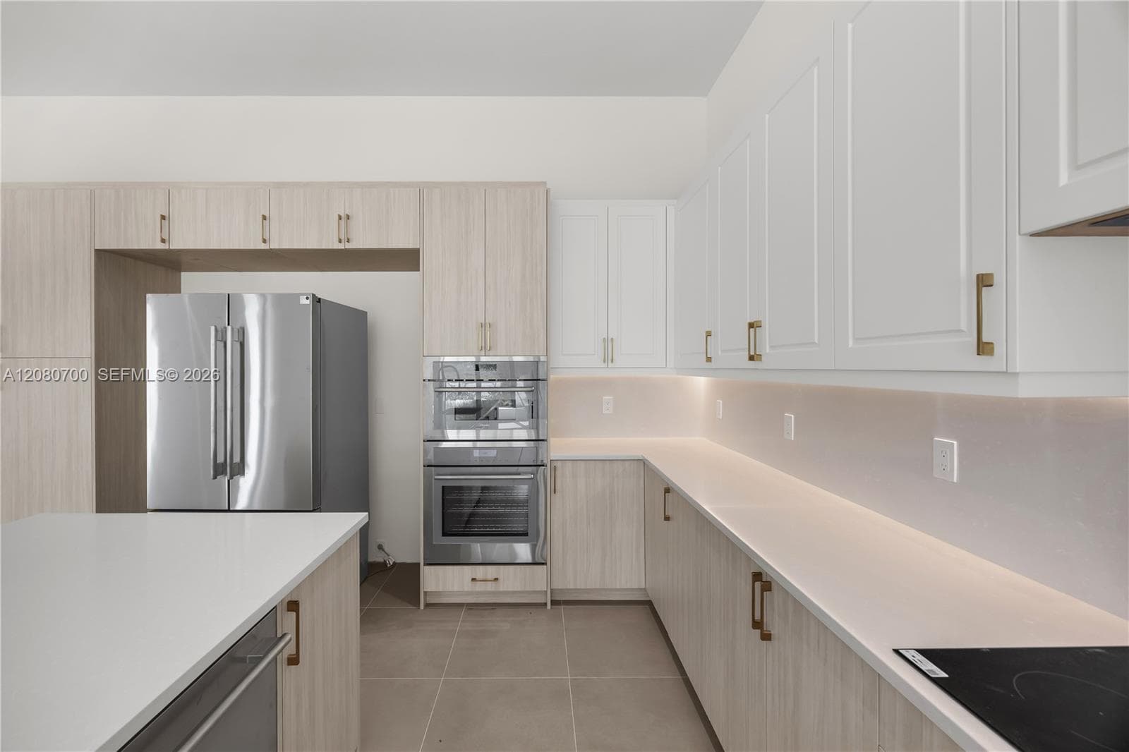 Modern kitchen featuring two-toned cabinetry, stainless steel appliances, and integrated under-cabinet lighting