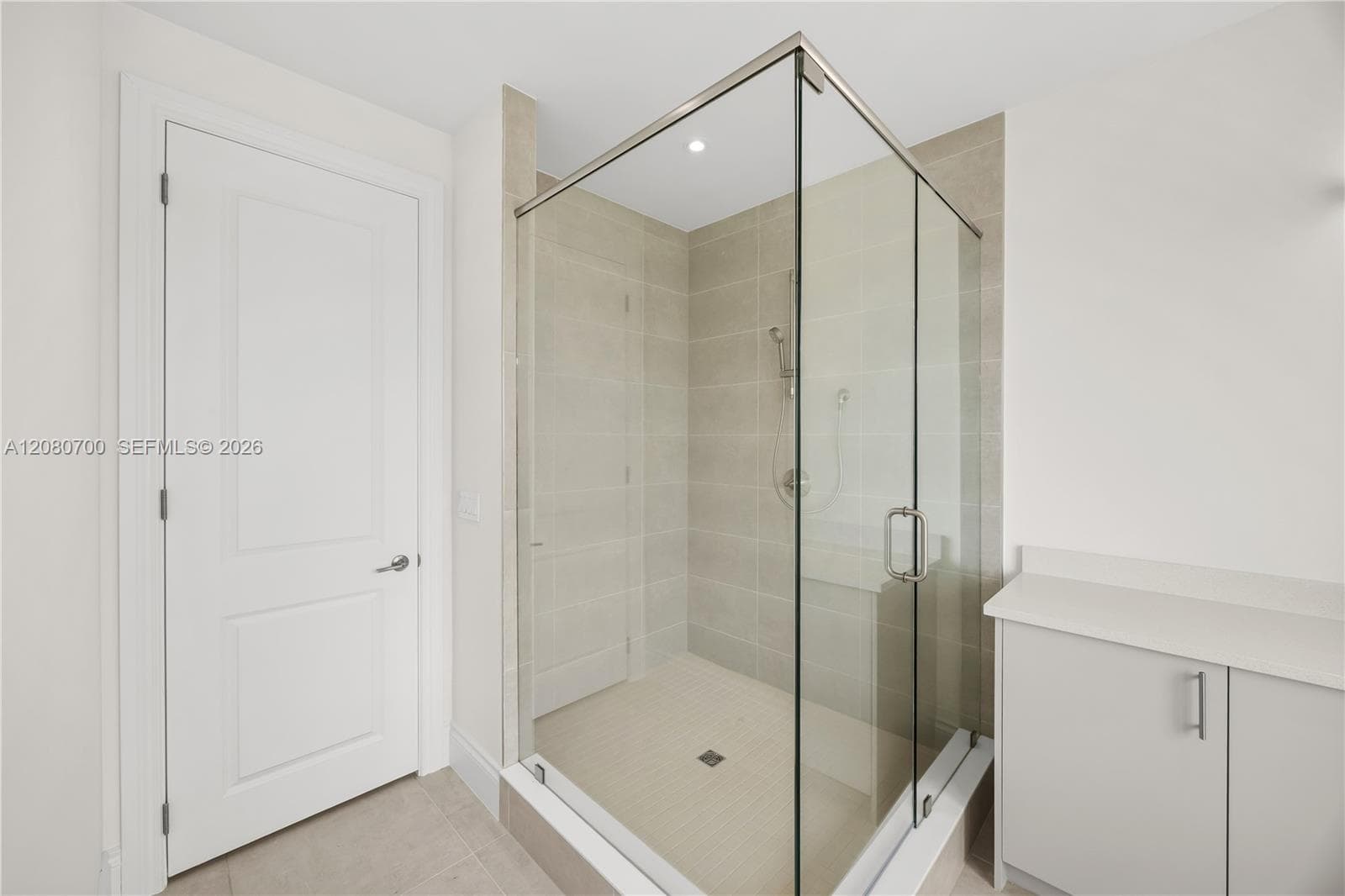 Glass-enclosed shower with a built-in bench, tiled walls, and a rainfall showerhead