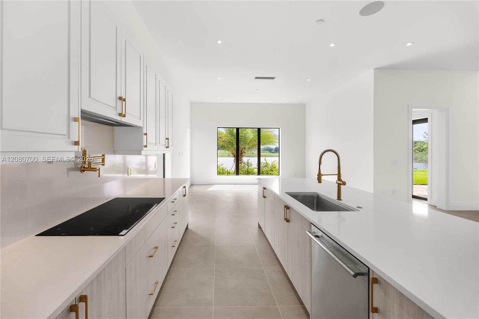 Modern kitchen with white cabinetry, gold-finish hardware, built-in cooktop, and an integrated dishwasher