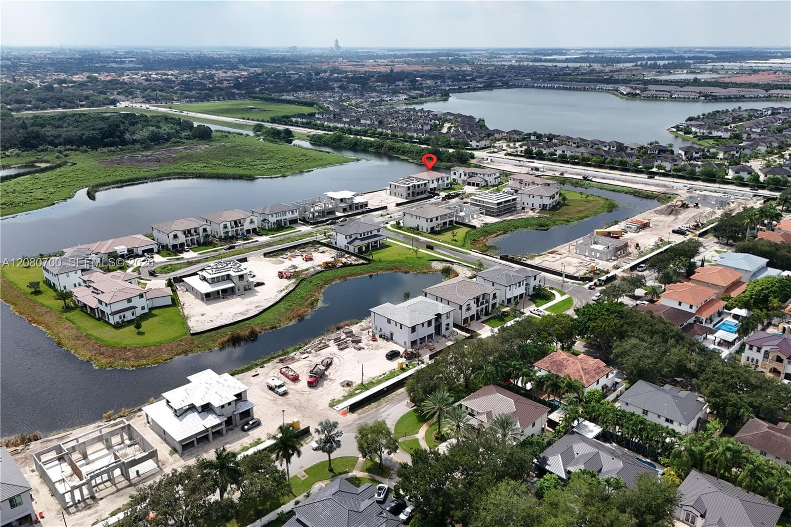 Waterfront community with established homes and ongoing construction, featuring a prominent body of water and surrounding green spaces