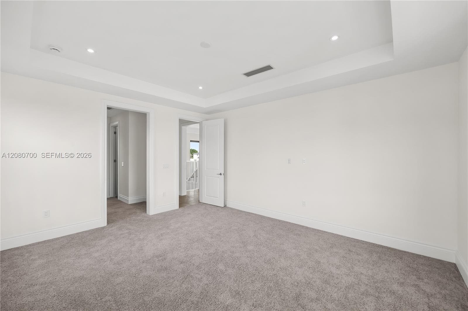 Recessed lighting, tray ceiling, neutral carpet, white walls, and white trim