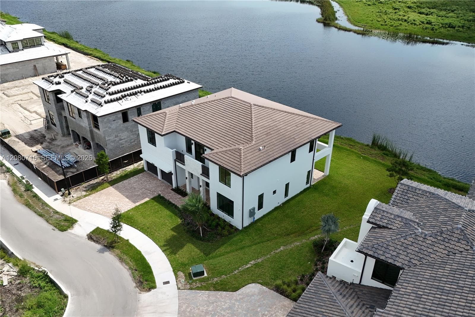 White exterior with a tiled roof, paver driveway, and a private balcony