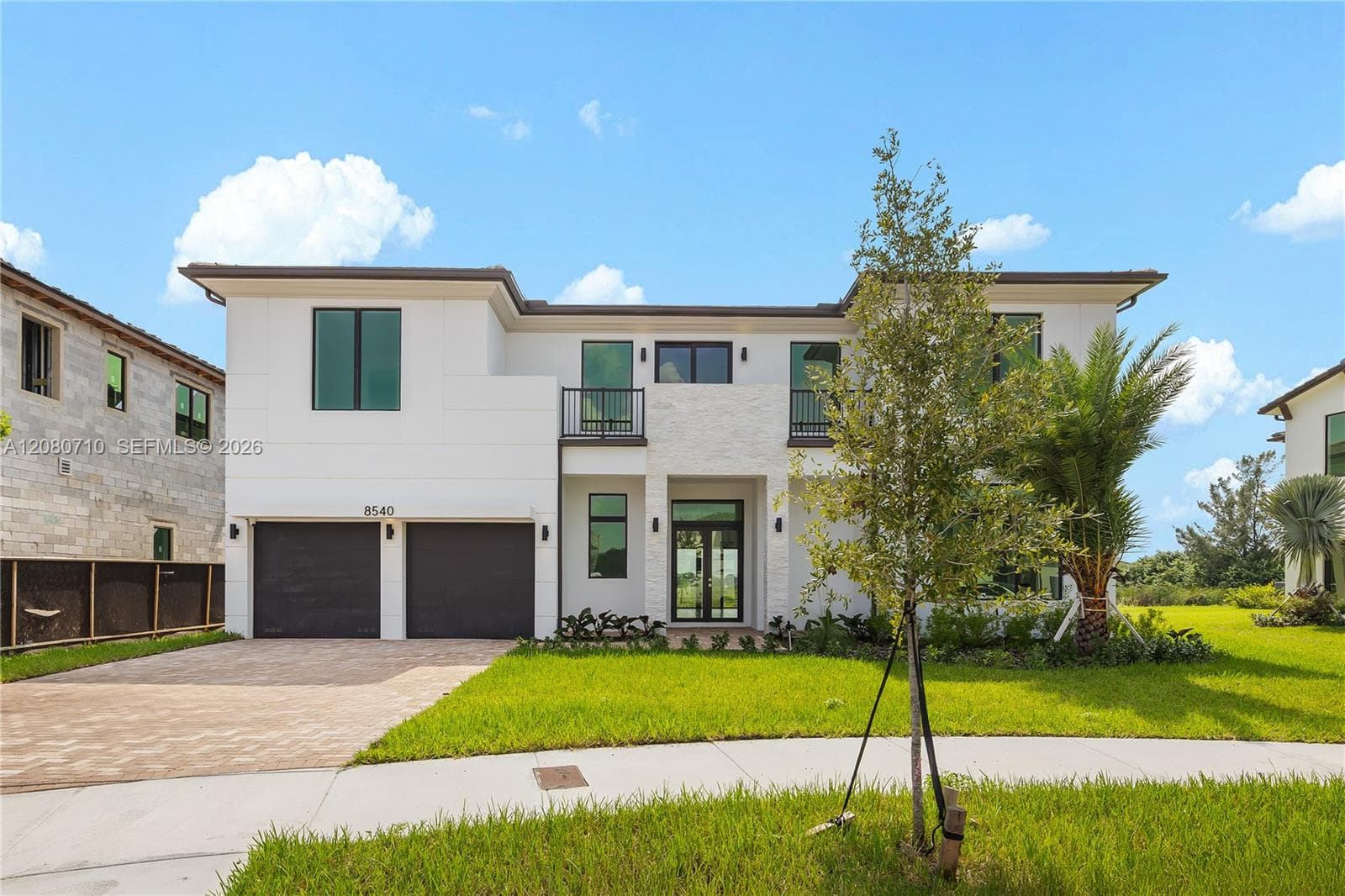 Modern exterior architecture with a white facade, black-framed windows, and a paver driveway