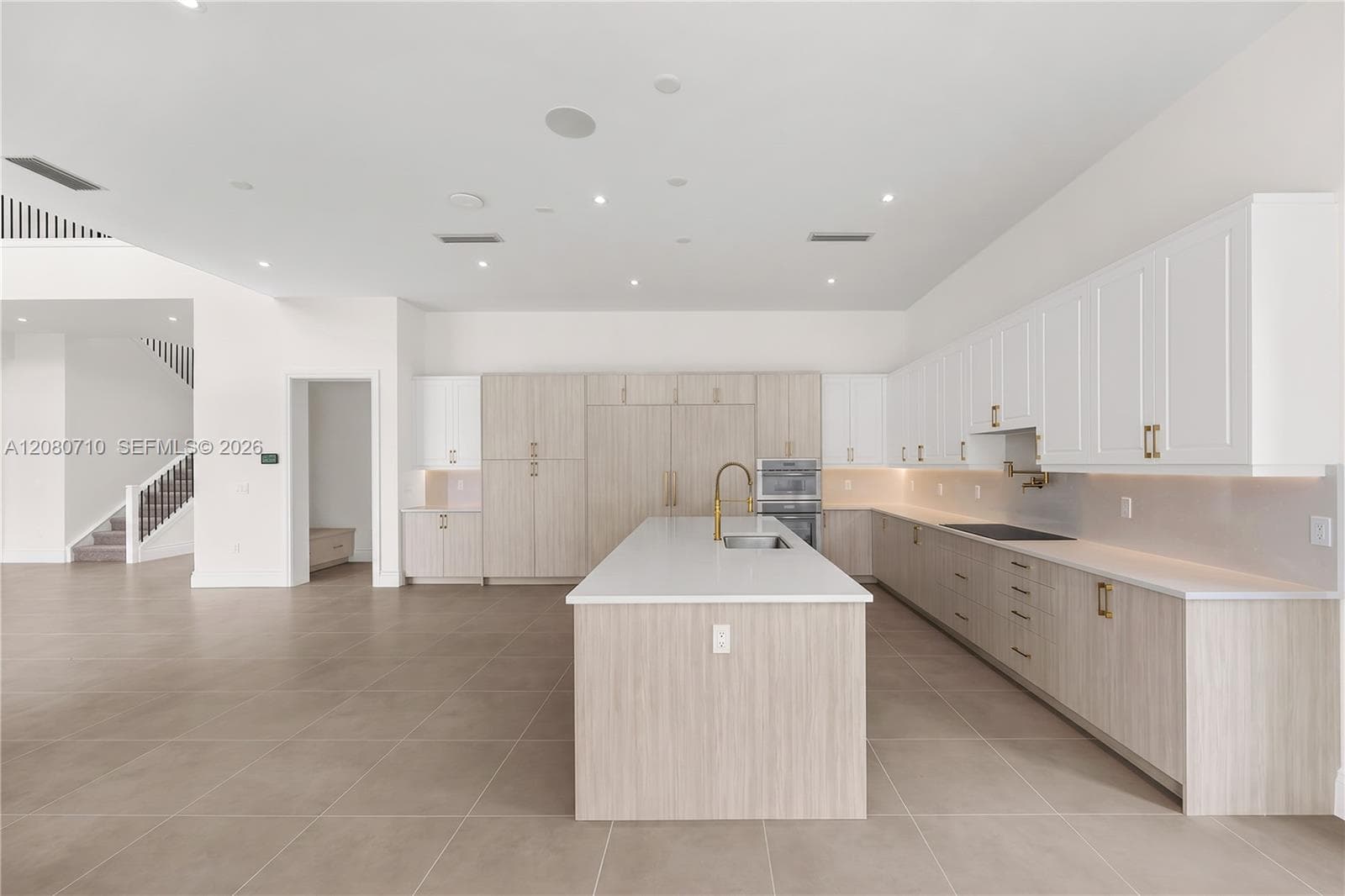 Spacious kitchen featuring an expansive center island, integrated appliances, extensive cabinetry, and tile flooring