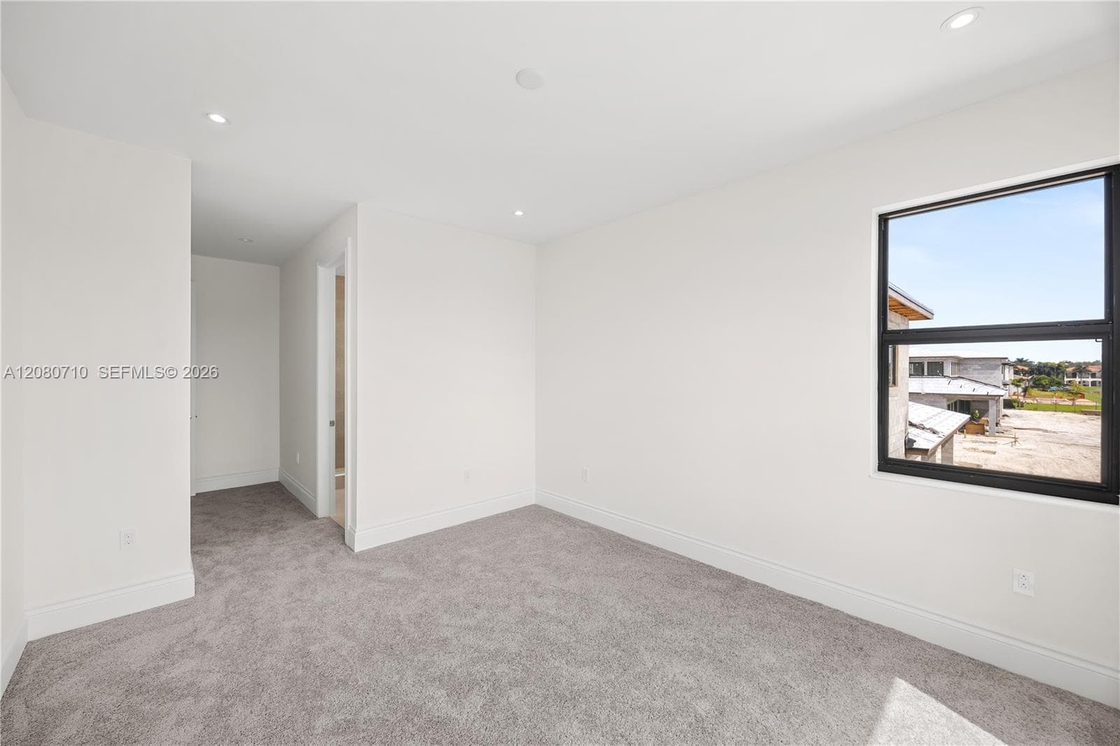 Plush gray carpeting, white painted walls, recessed ceiling lighting, and a dark-framed window