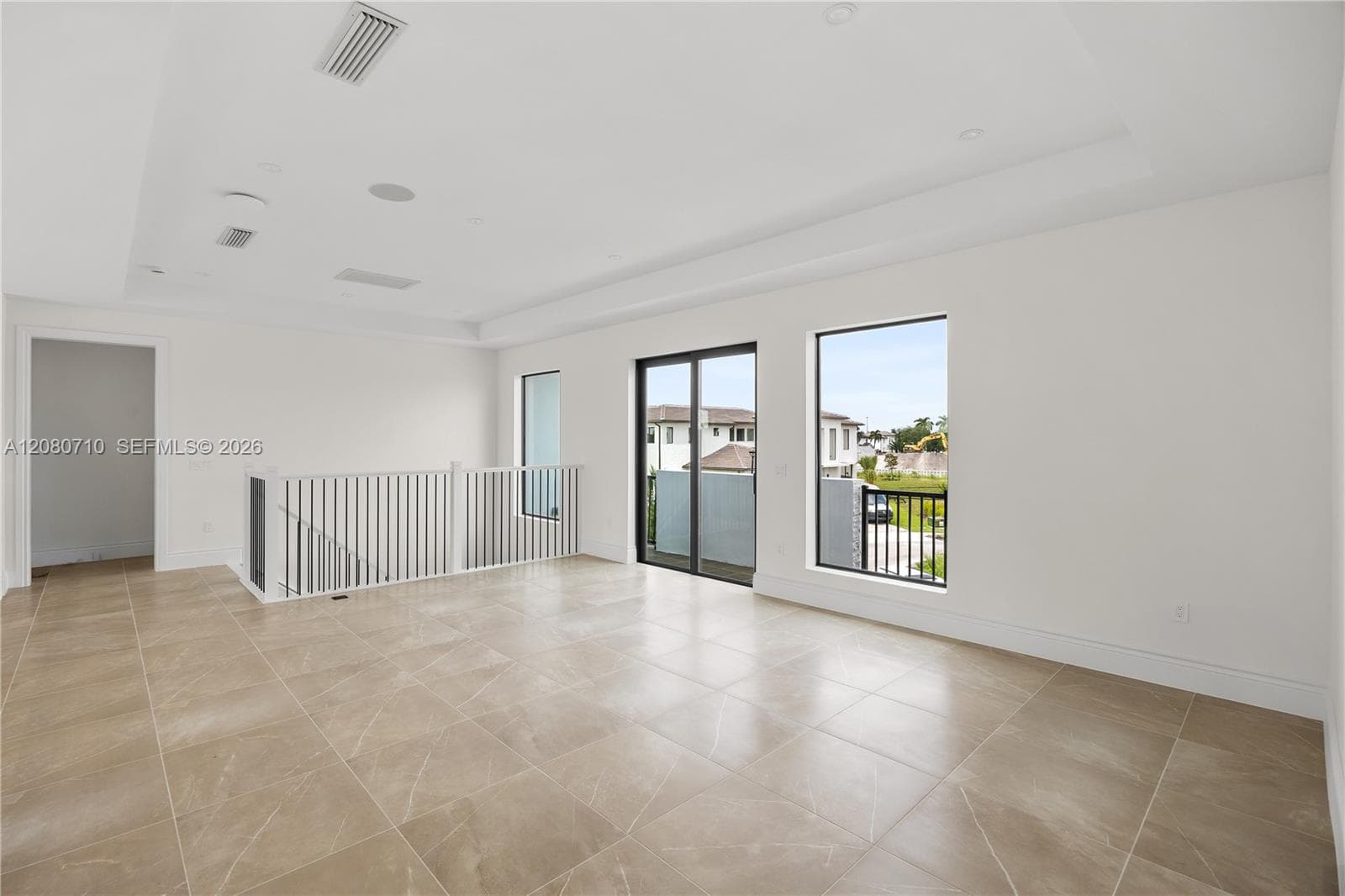 Expansive open space featuring tile flooring, a contemporary railing, recessed lighting, and a glass sliding door