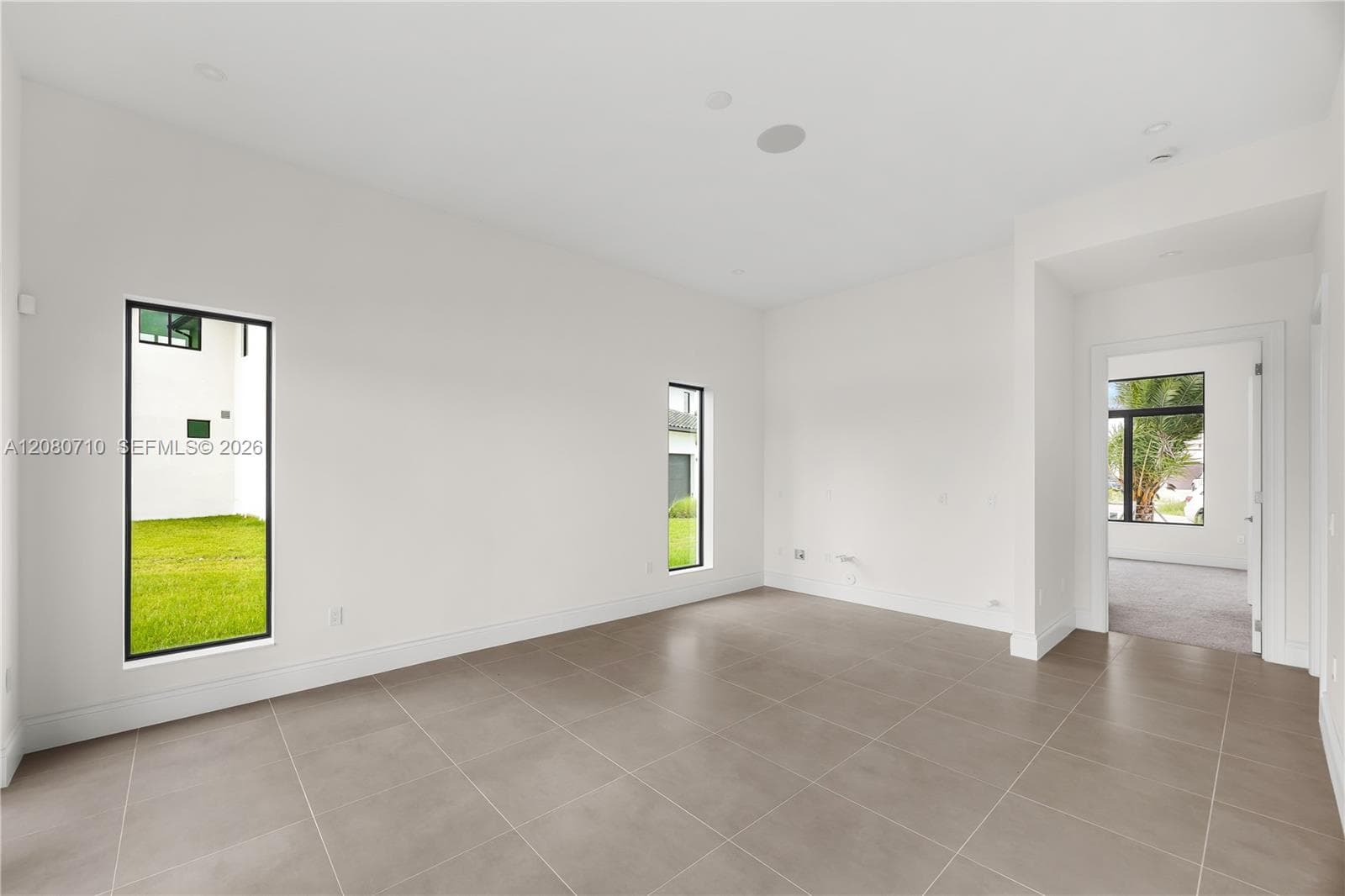 Spacious room featuring tile flooring, white walls, recessed lighting, and narrow vertical windows