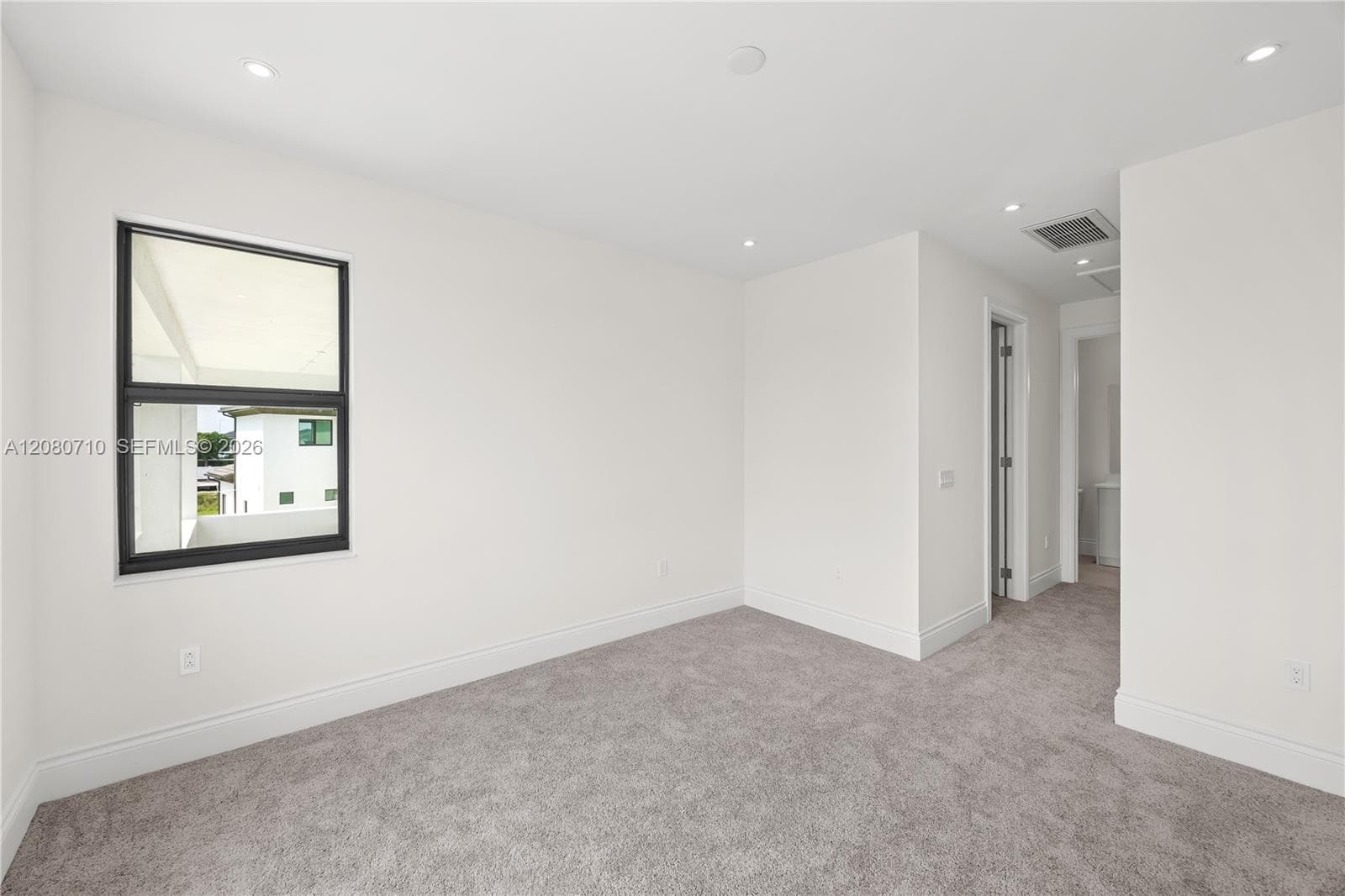Recessed ceiling lighting, dark-framed window, neutral gray carpeting, and white painted walls