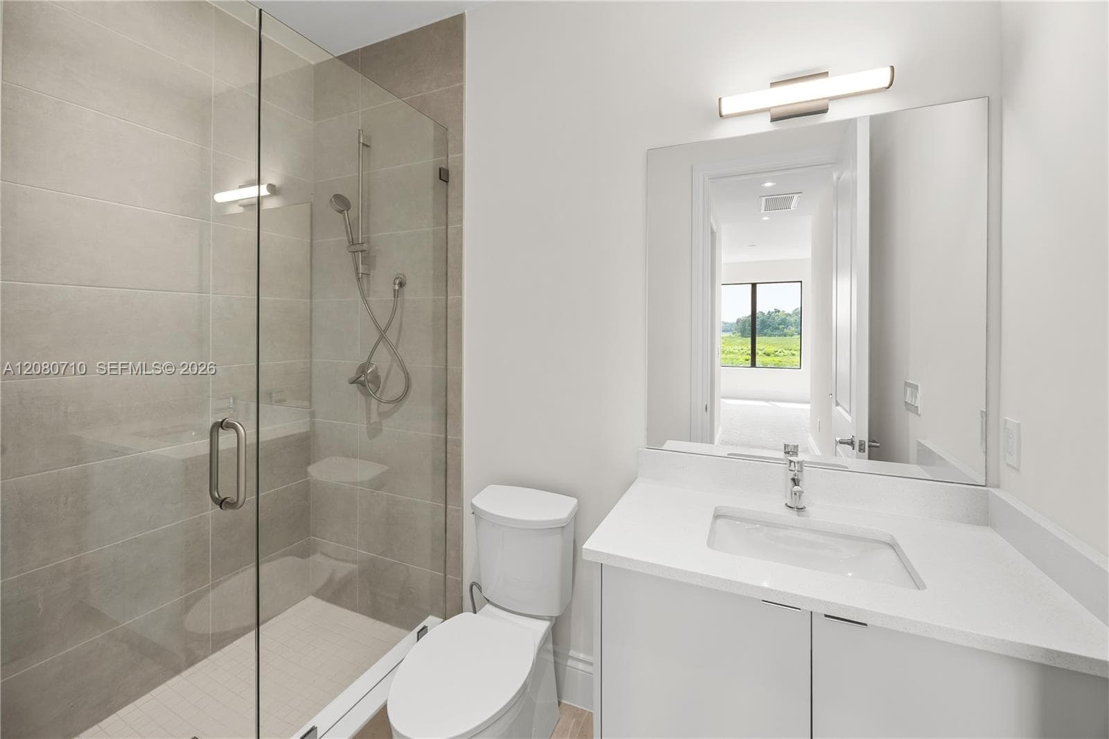 Walk-in shower with clear glass enclosure and tile surround