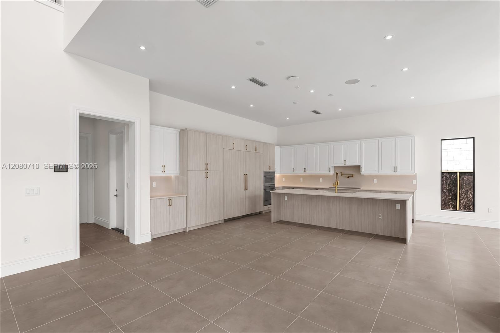 Open-concept kitchen featuring an expansive island, integrated appliances, recessed lighting, and tile flooring