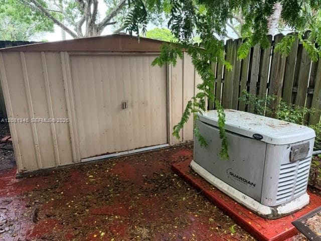 Storage shed with a pitched roof and a permanently installed generator unit on a solid base