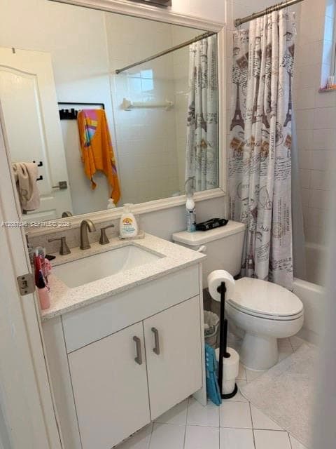White tiled flooring, vanity with light-colored countertop, undermount sink with brushed nickel faucet, wall-mounted mirror with white frame, and a built-in bathtub with white tile surround