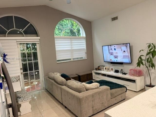 Vaulted ceilings, arched windows, sliding glass door, tiled flooring, and a ceiling fan