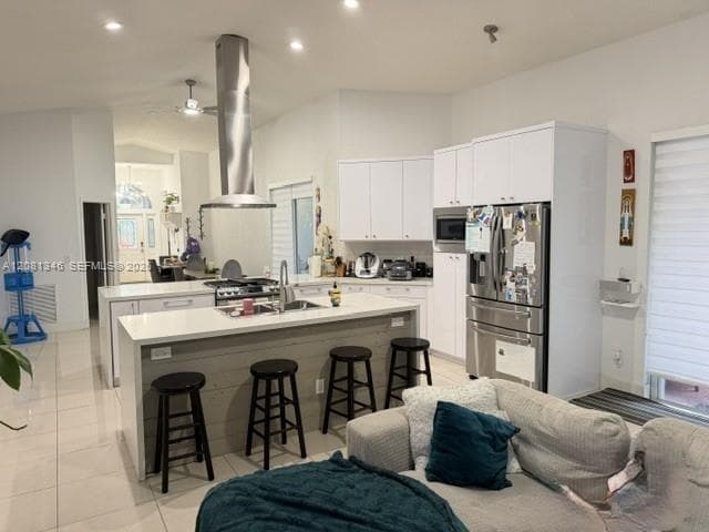 Kitchen featuring white cabinetry, stainless steel appliances, a center island with seating, and recessed lighting