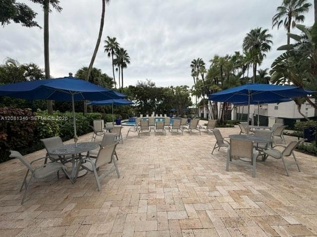 Expansive paver patio with a herringbone pattern, surrounded by lush landscaping and mature palm trees