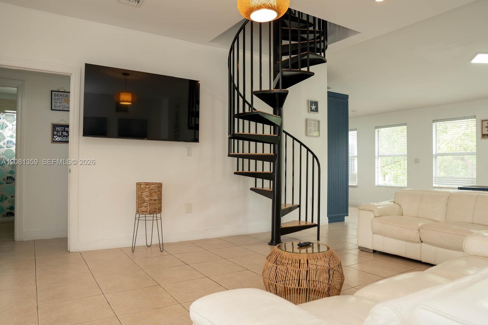 Black metal spiral staircase with wood-finish treads, neutral ceramic tile flooring, and integrated recessed lighting