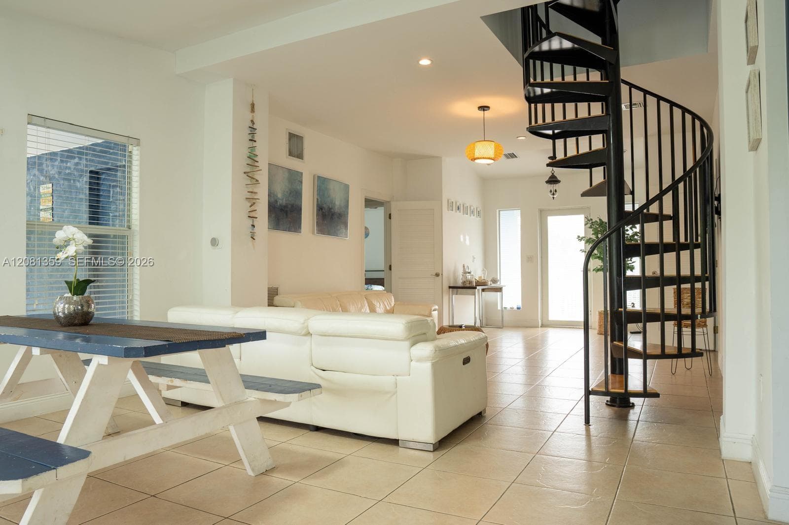 Open floor plan featuring a black metal spiral staircase, large format tile flooring, recessed lighting, and a glass-paneled exterior door
