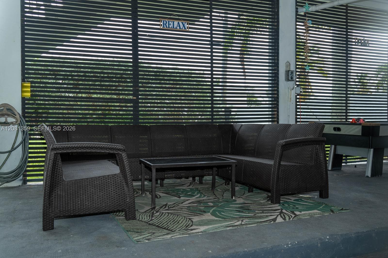 Covered outdoor area featuring concrete flooring and black louvered privacy screening