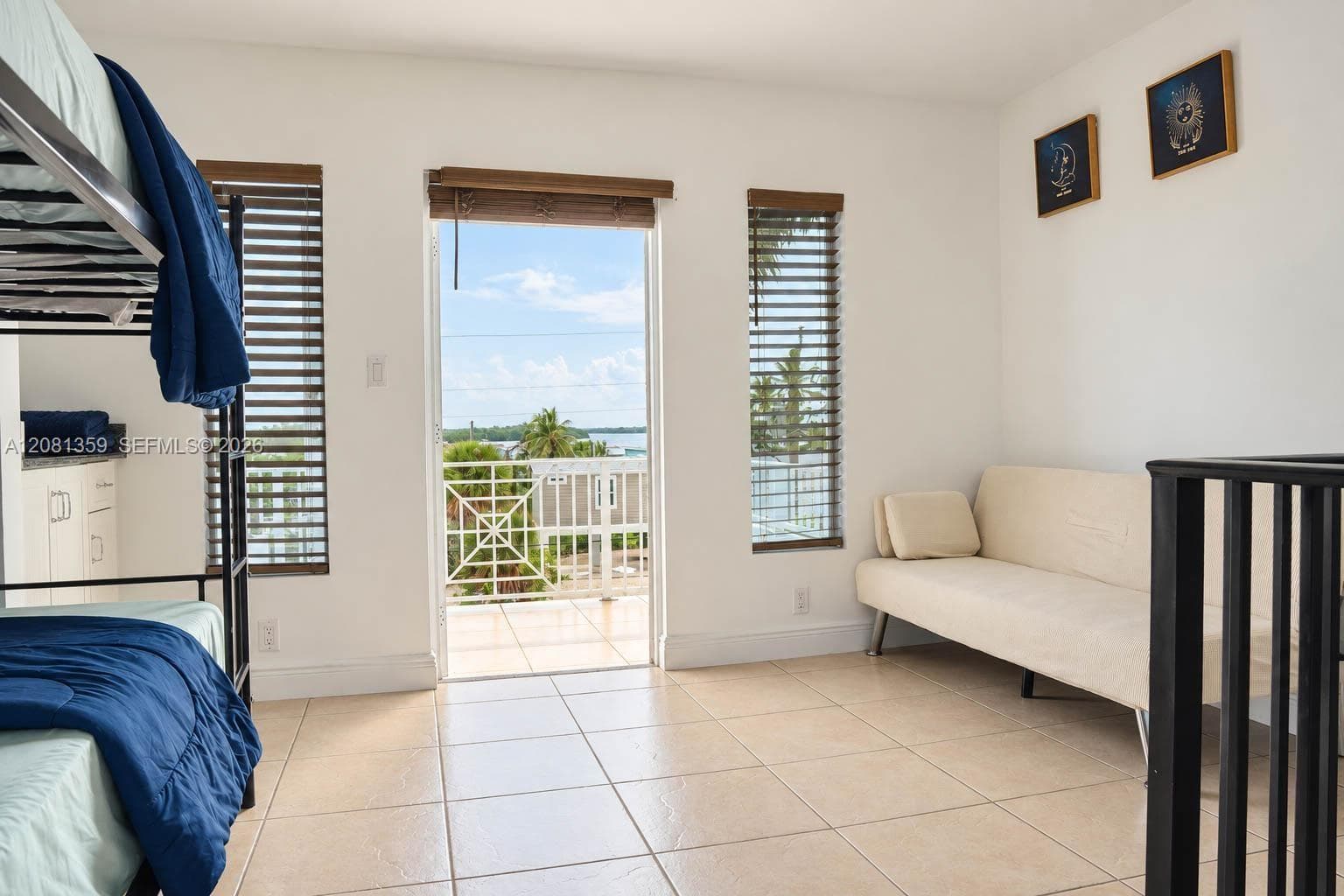 Room featuring large-format tile flooring, built-in cabinetry with stone-finish countertops, horizontal blinds, and a glass-paned door providing access to an exterior balcony