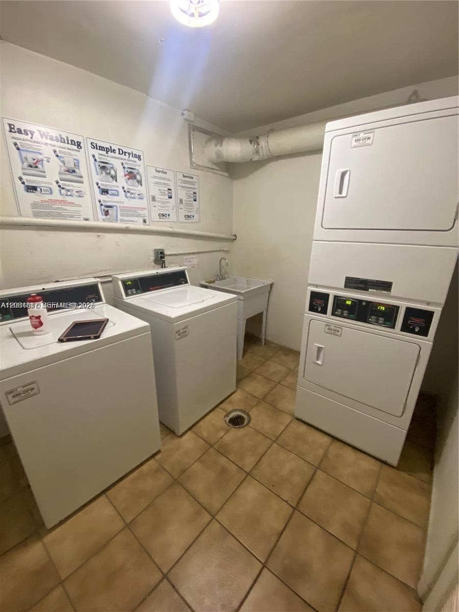 Laundry area featuring two top-load washing machines, a stacked laundry center, a utility sink, and tile flooring
