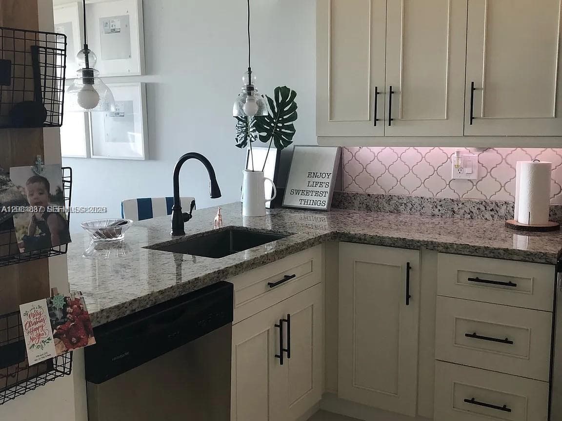 Kitchen featuring light-toned shaker cabinetry, stone-finish countertops, matte black hardware, an undermount sink with a gooseneck faucet, and patterned tile backsplash