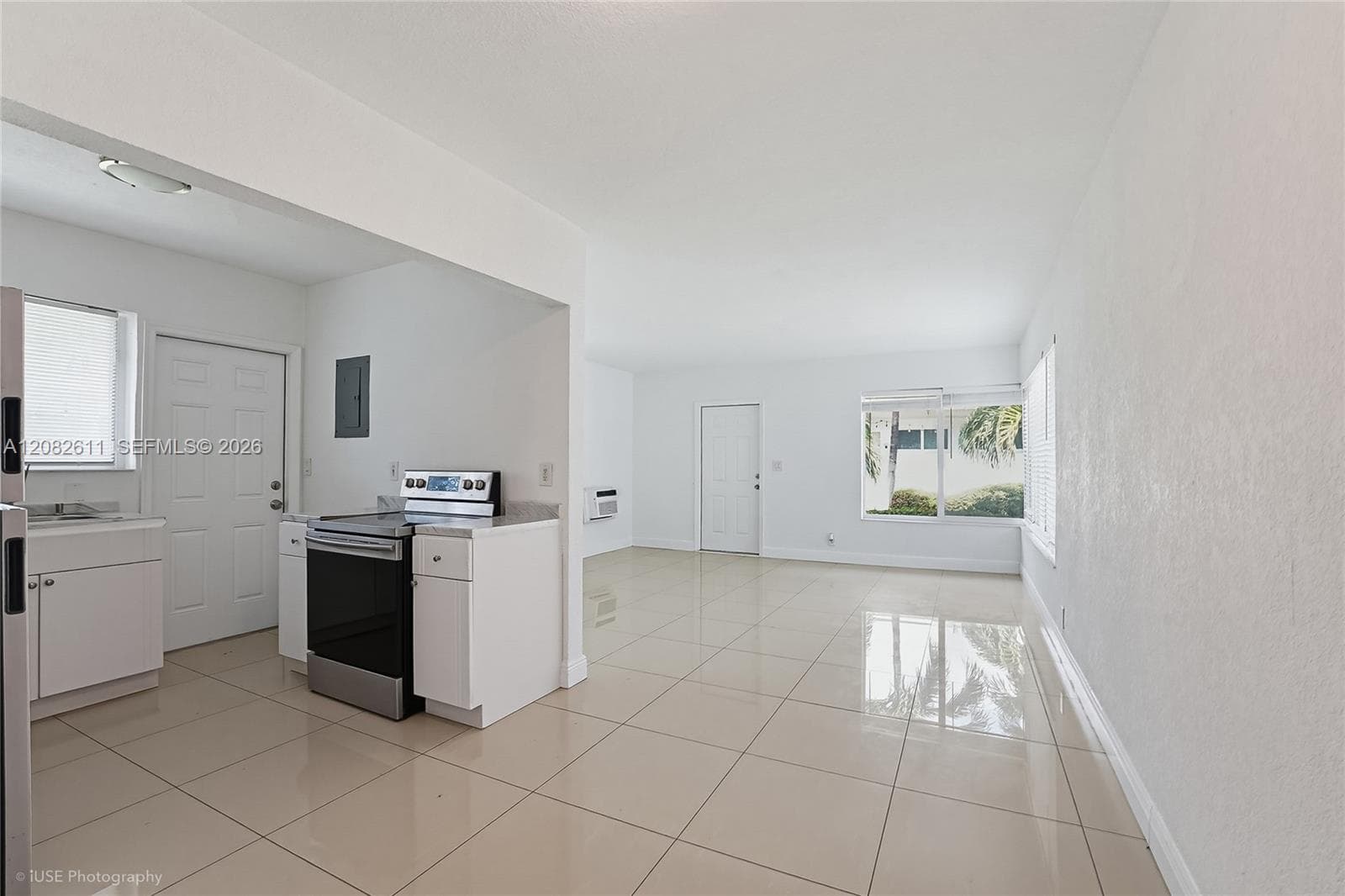 Open-concept interior featuring large-format tile flooring, stainless steel range, white cabinetry, and multi-pane windows