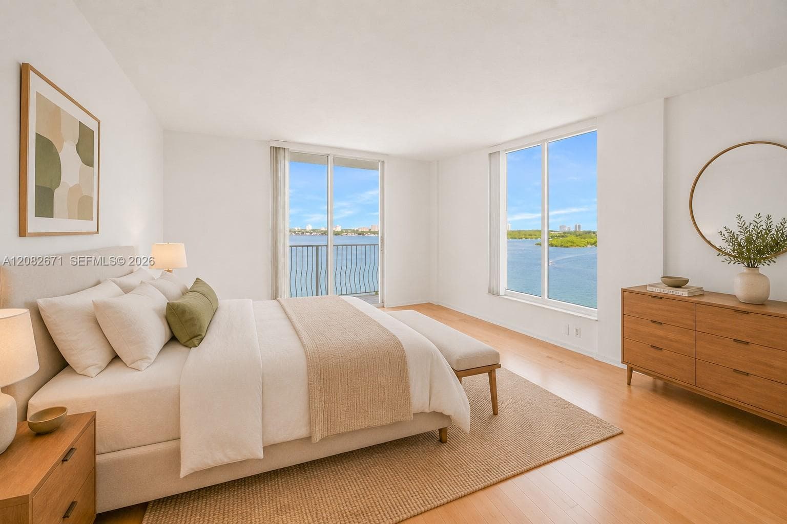 Primary suite, digitally staged, with direct bay views and mirrored closet wall.