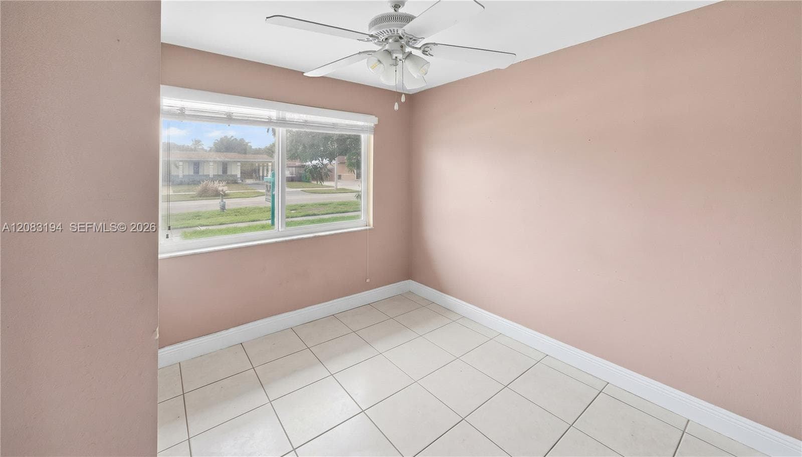 Room featuring ceramic tile flooring, a large window, and a ceiling-mounted light fixture with fan blades