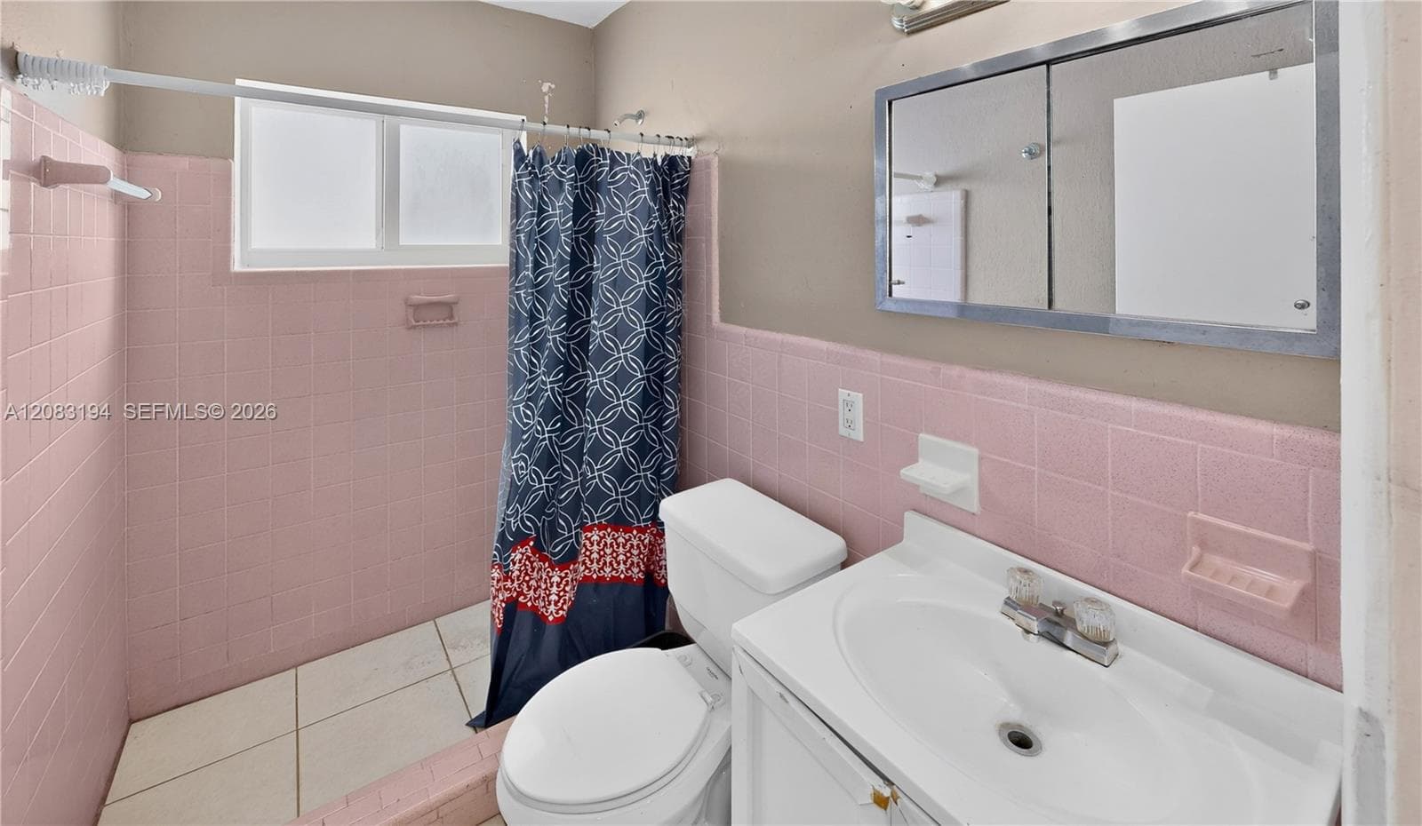 Bathroom featuring wall-mounted medicine cabinet with mirrored doors, white integrated vanity sink, horizontal tile surrounds, and sliding window