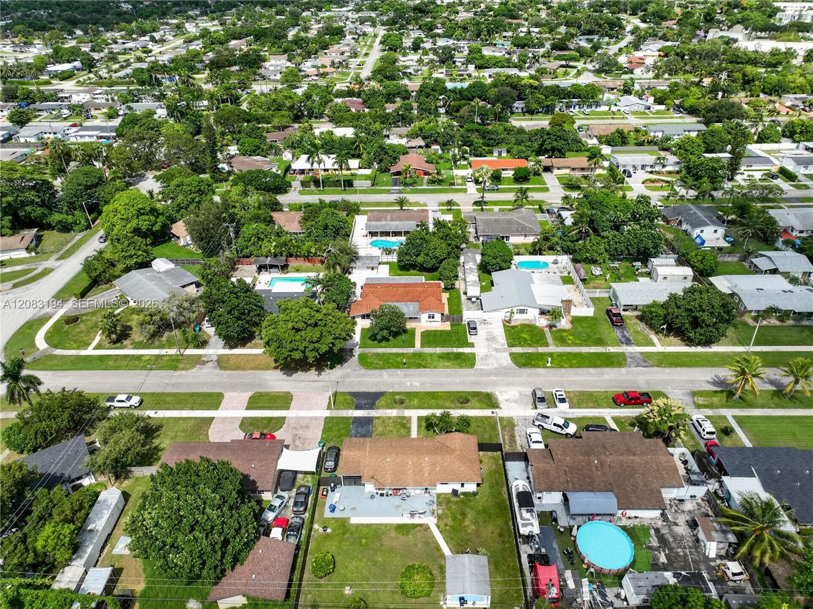 Aerial perspective of a suburban neighborhood featuring tree-lined streets, established residential lots, and proximity to regional vegetation
