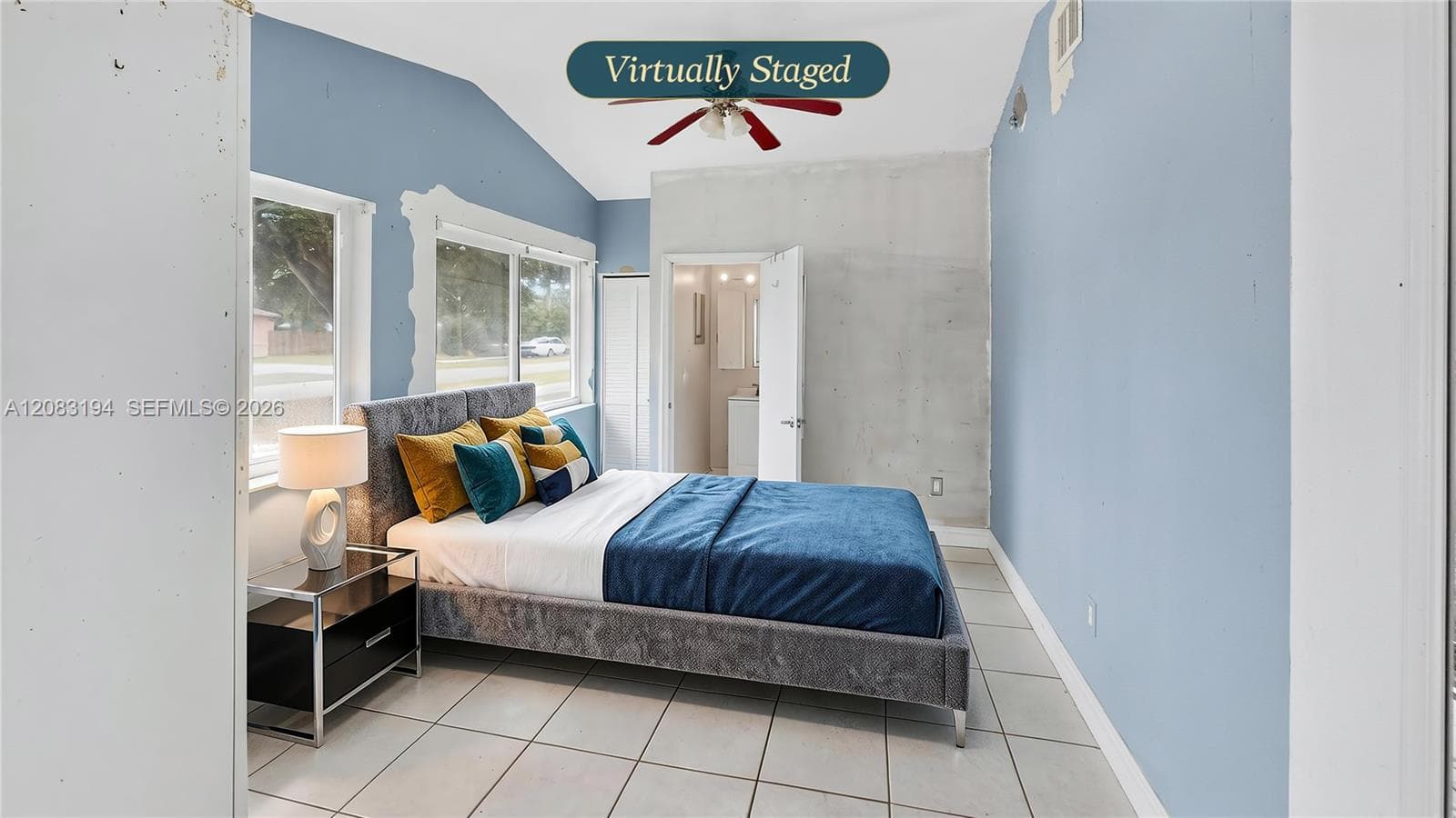 Room featuring vaulted ceilings, large windows, tile flooring, and a ceiling fan