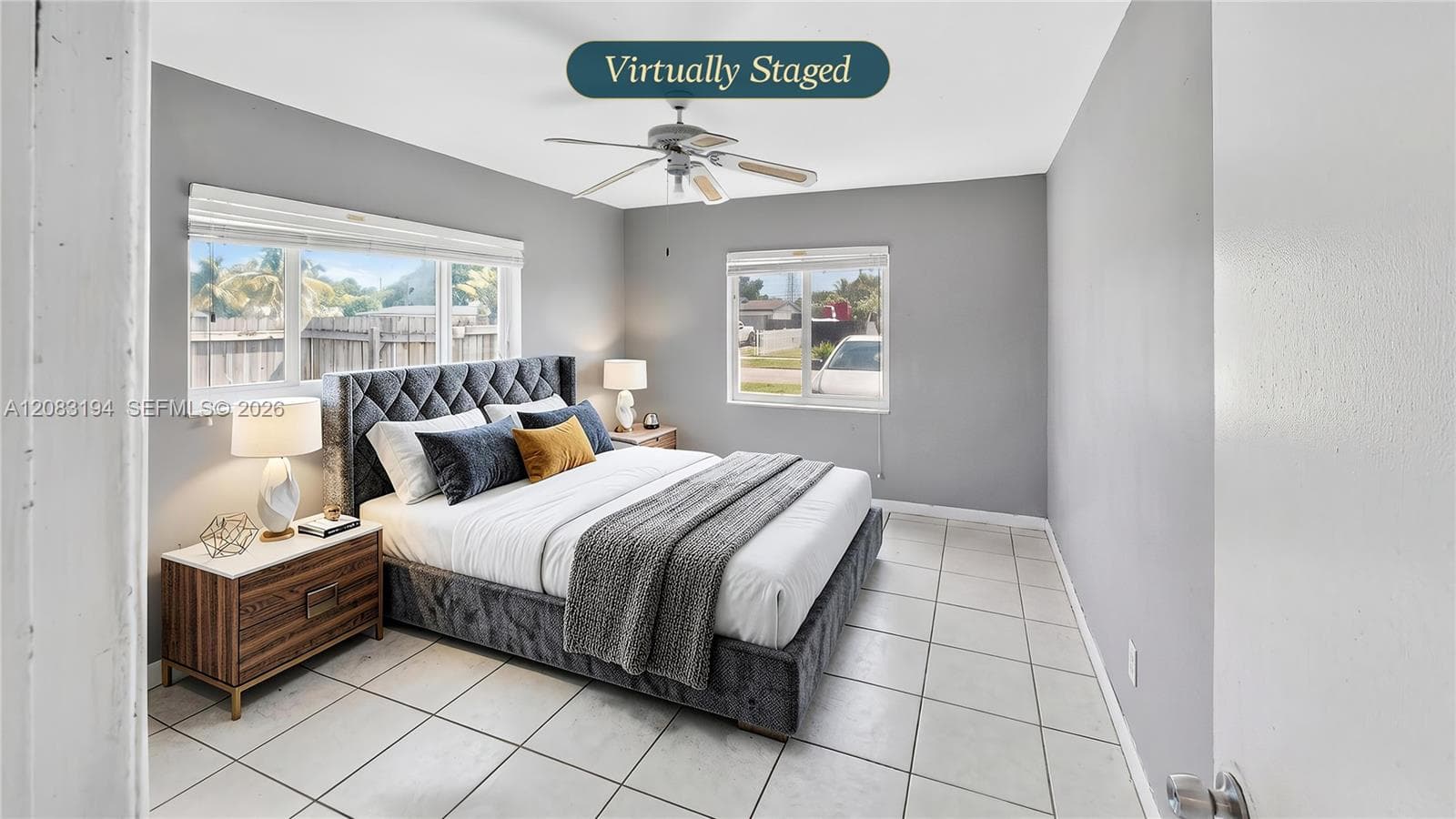 Neutral-toned room featuring large-format tile flooring, dual-aspect windows, and a ceiling-mounted light fixture with integrated fan